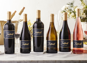 Lineup of Fortunati wine bottles with ice bucket and flowers in the background